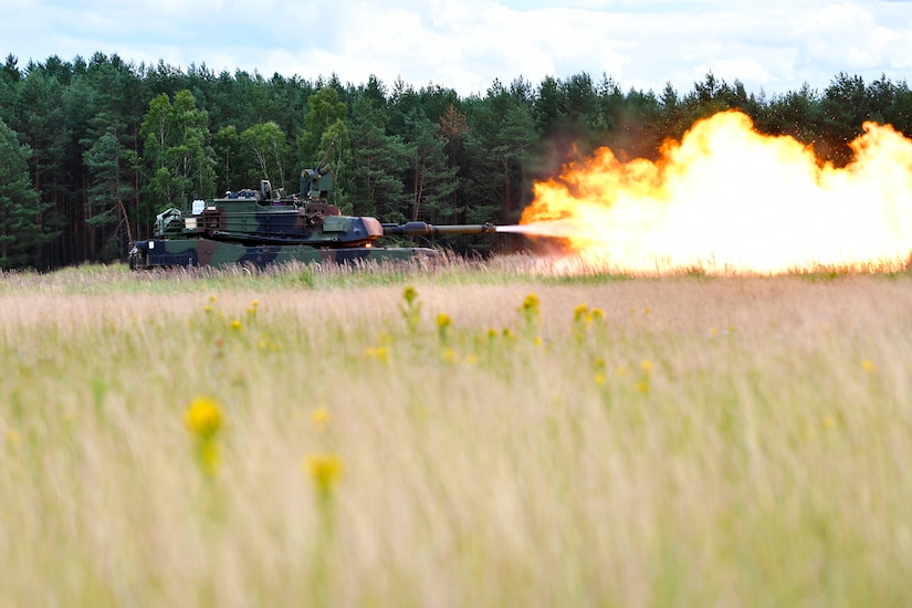 A tank fires a large blast in the middle of a field.