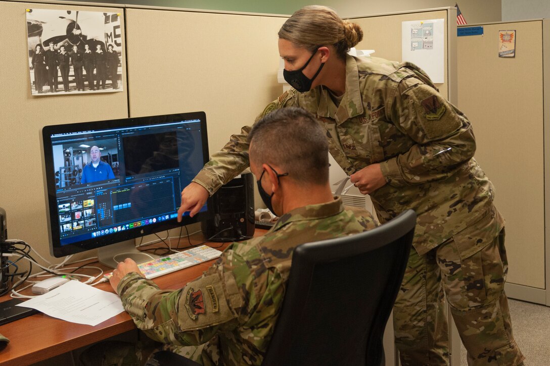 Photo of an Airman helping Chief Wilfong edit a video