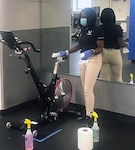 Kimberly LaCour, 502nd Force Support Squadron recreation fitness specialist, cleans and sanitizes a stationary bike at the Joint Base San Antonio-Lackland Warhawk Fitness Center.