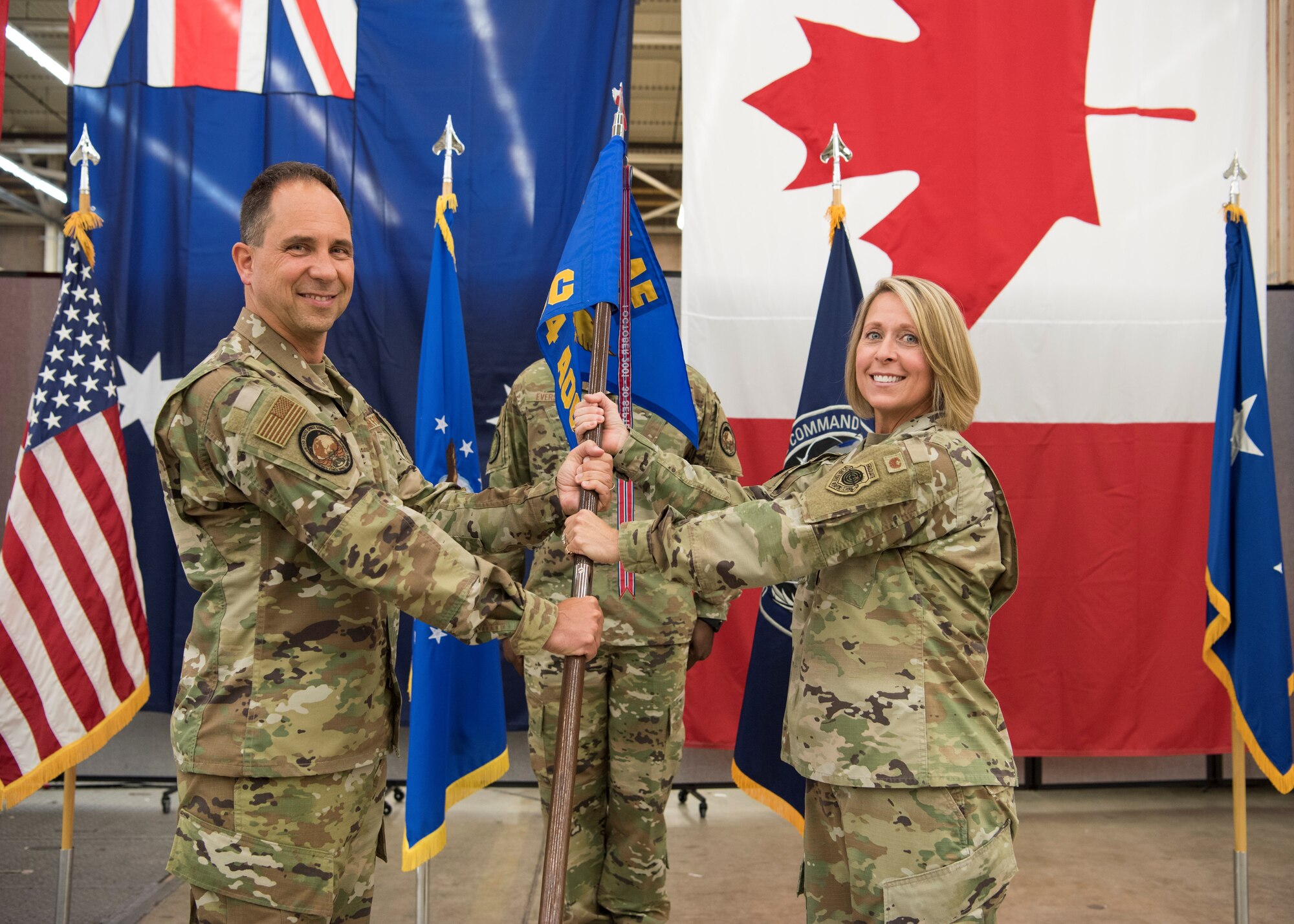 Col. Monique C. DeLauter, incoming Director, Combined Space Operations Center, and Commander, 614th Air Operations Center (right), receives the guidon from Maj. Gen. John E. Shaw, Commander, Combined Force Space Component Command and Space Operations Command (left)