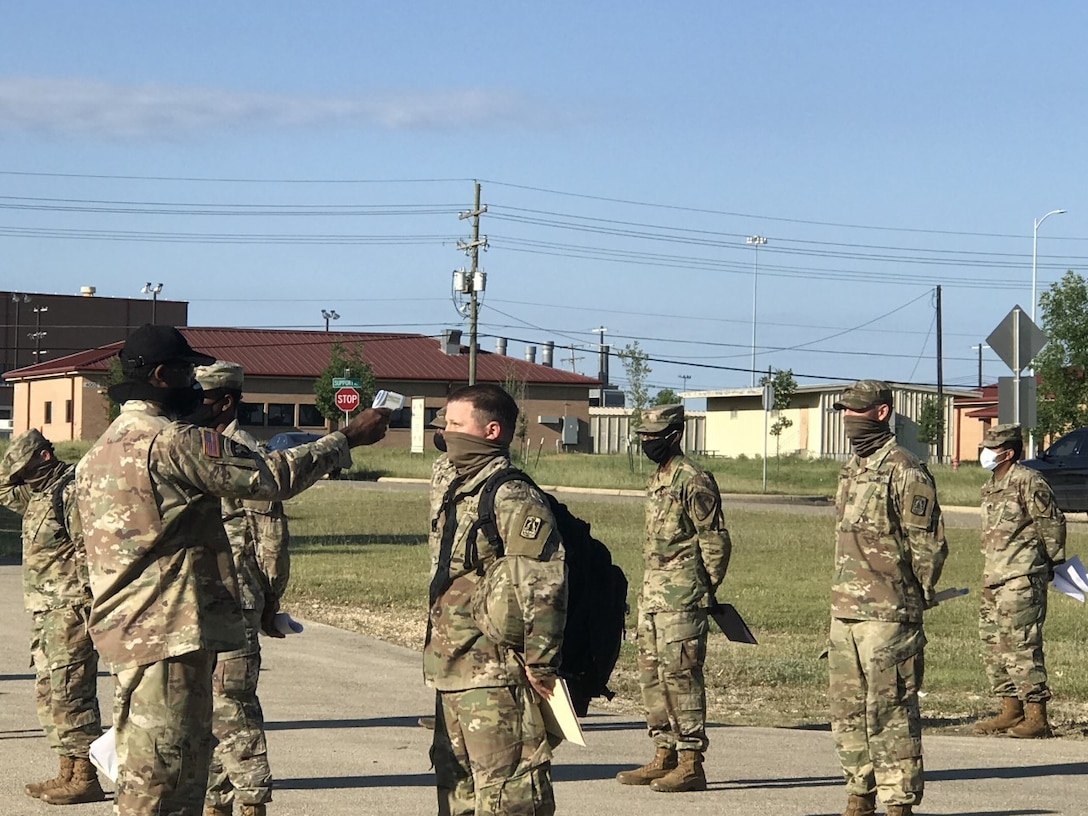 An instructor assigned to a brigade within the 94th Training Division - Force Sustainment checks the temperature of students attending a course at Fort Hood, Texas, May 6-22, 2020. For the 2nd Brigade (Transportation), 94th TD-FS new commander, Lt. Col. Eddie Smith is more focused on Soldiers and their well being versus a a change of command ceremony.