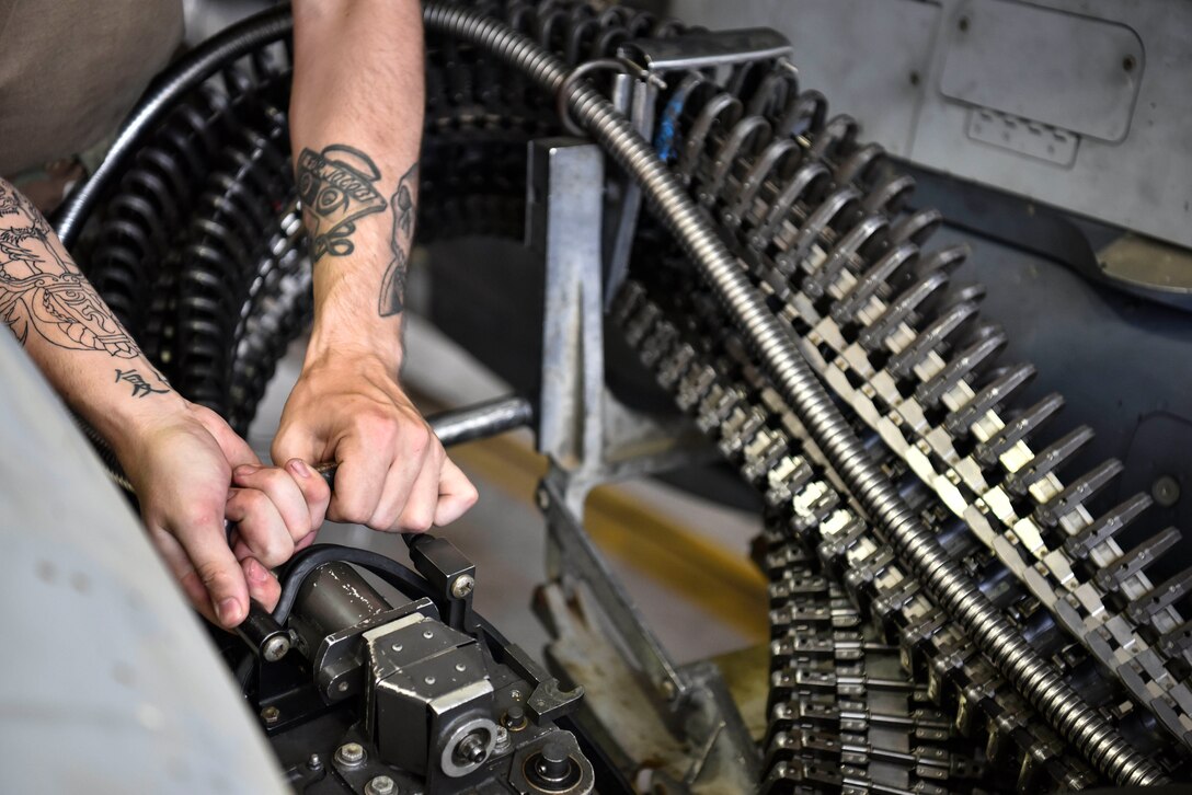 A photo of an Airman connecting a gun system onto aircraft.
