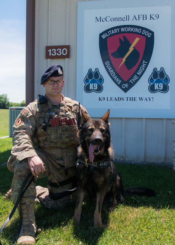 Staff Sgt. Michael Smith, 22nd Security Forces Squadron military working dog trainer, and his partner Drago, a nine-year-old German Sheppard SFS MWD, pose together for a photo July 13, 2020, at McConnell Air Force Base, Kansas. Smith and Drago have been partners since February 2020 and train 8-13 hours daily on security patrols, drug detection and explosive sweeps. (U.S. Air Force photo by Senior Airman Alexi Bosarge)