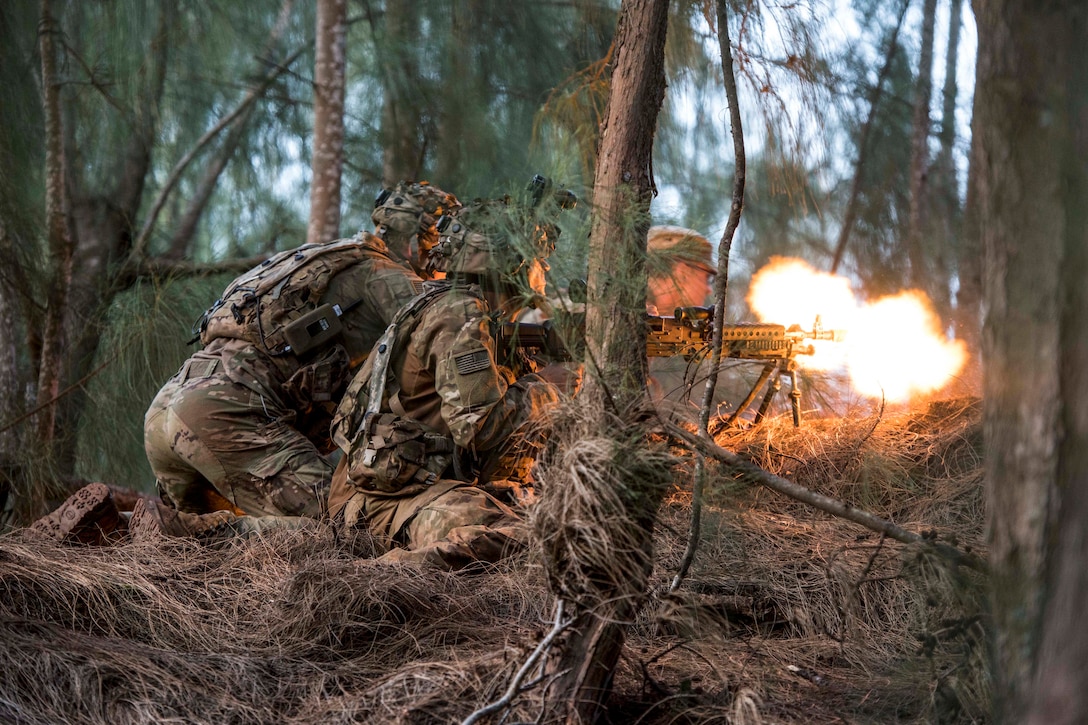 A ball of flames lights up a forested area as crouching soldiers fire a weapon.