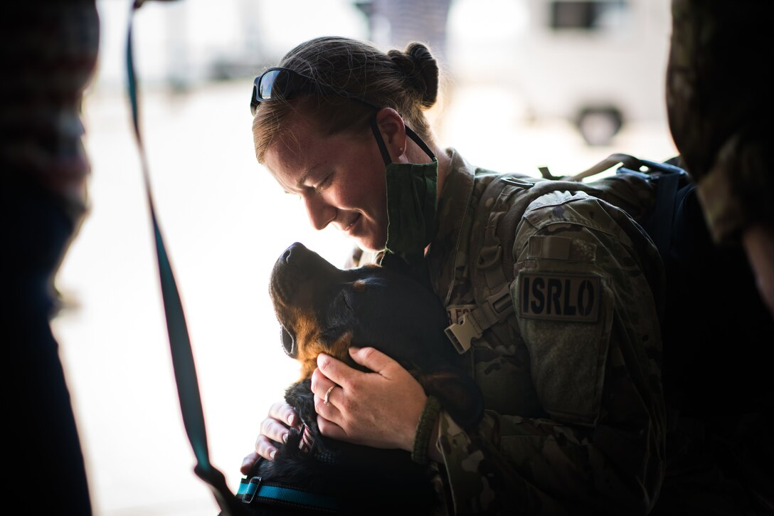 A guardsman hugs a dog.