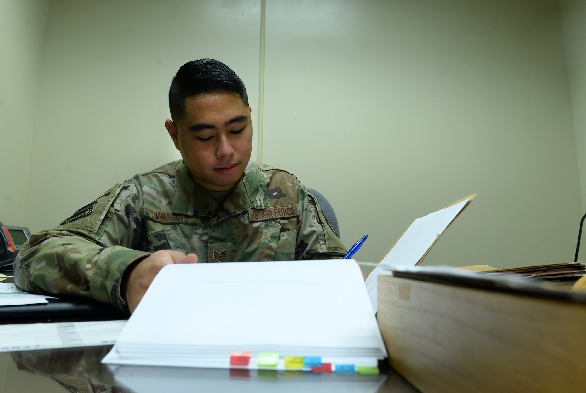 Airman sits at desk looking a file.