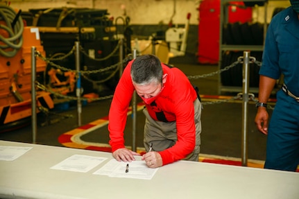 Lt. Cmdr. Paul Castillo, USS Gerald R. Ford's Ordnance Handling Officer, signs turnover paperwork to take possession of Lower Stage Weapons Elevator Lower Stage Weapons Elevator (LSWE), July 22, 2020