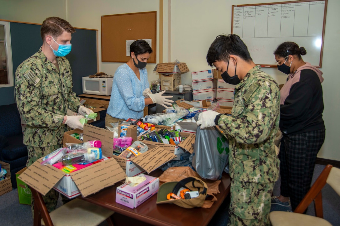 Four people wearing face masks pack items into boxes.