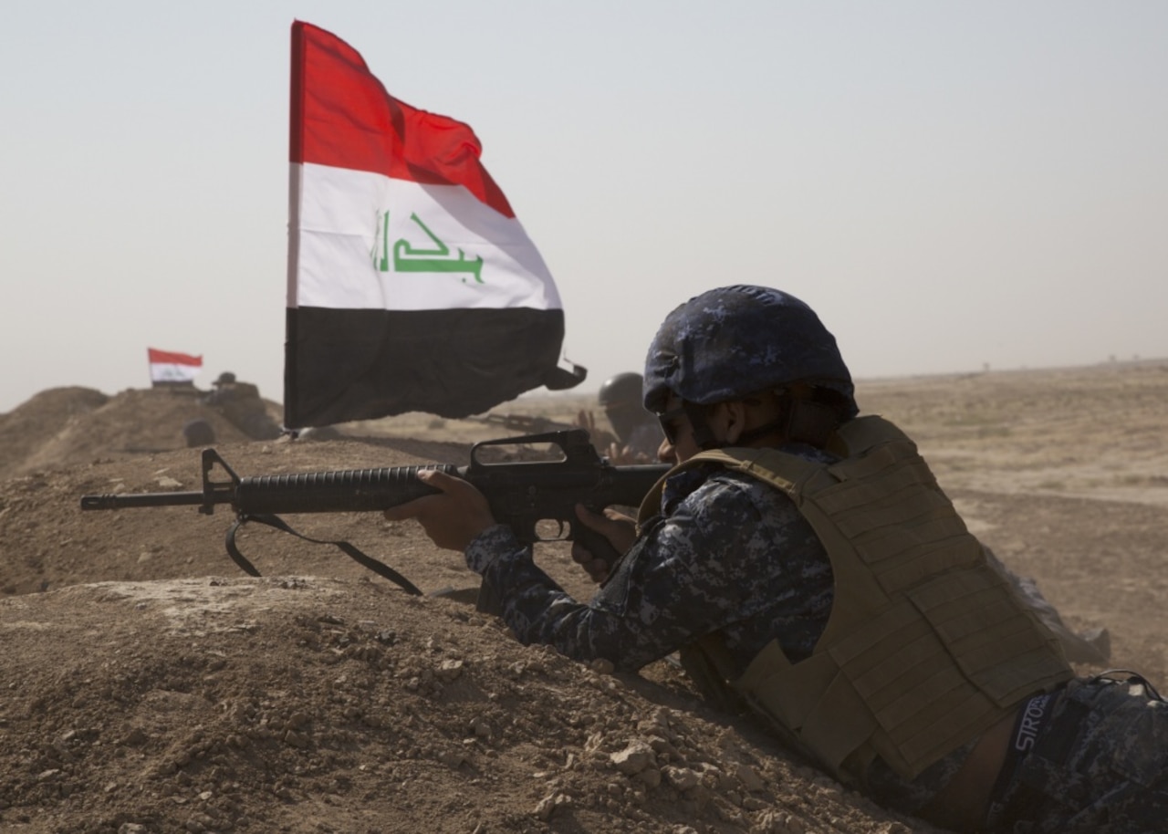 A member of the Iraq Federal Police aims a gun.