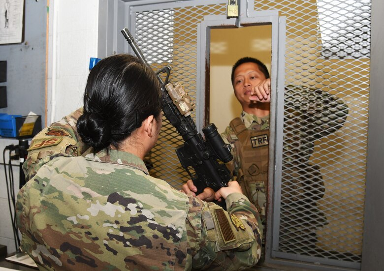 A photo of an Airman handing a weapon to another Airman.