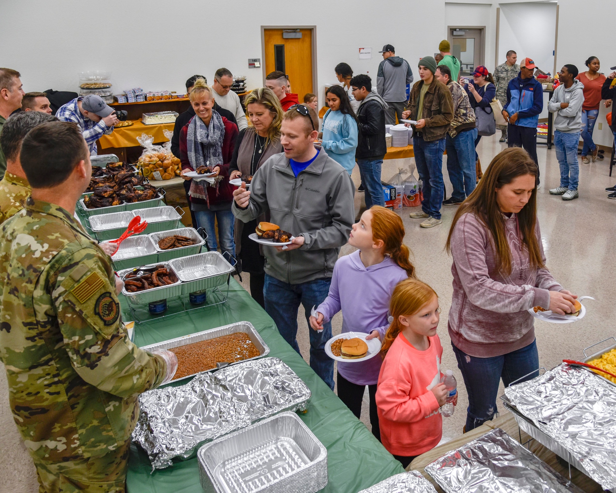 Airmen and their family members line up along the food buffet at the family day event held on Nov. 2, 2019, at Little Rock Air Force Base, Ark. The 913th Airlift Group hosted the event, celebrating and showing appreciation for family members' support of their Airmen. Nearly 80 percent of the unit are traditional reservists who live across the state and train one weekend a month, two-weeks a year. The Key Spouse program helps provide resources and activities for the event. (U.S. Air Force Reserve photo by Senior Airman Nathan Byrnes)