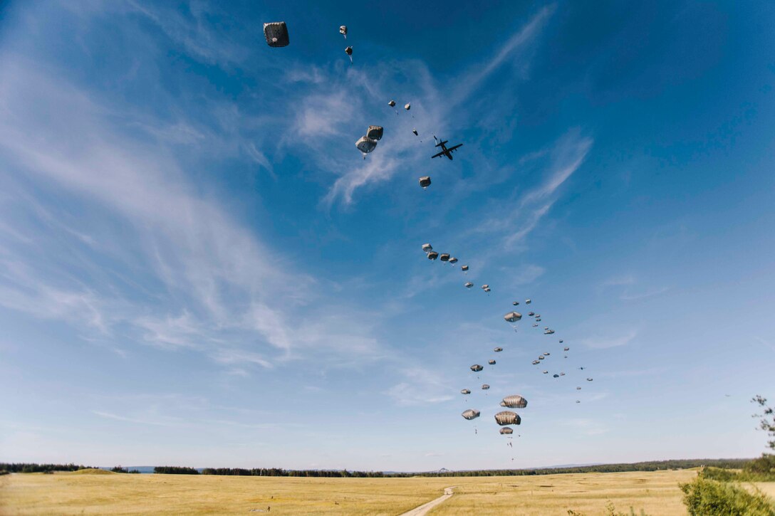 A group of soldiers with parachutes descend in the sky.