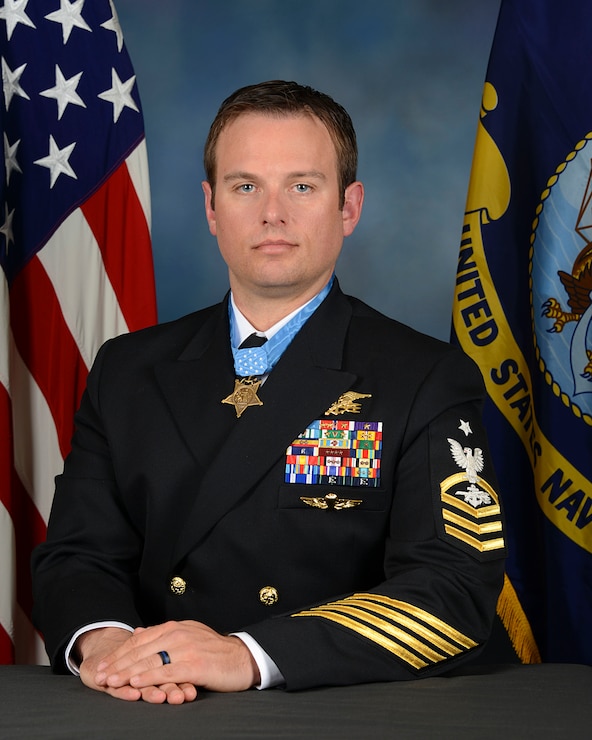 Senior Chief Special Warfare Operator Edward C. Byers, Jr., poses for a portrait with american flag in the background