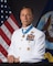 Britt Slabinski in uniform with medal of honor posing for the portrait with american and navy flags in the background