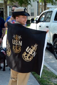 United States Navy Senior Chief Kerri Ayo, a native of Port St. Lucie, Florida, assigned to Navy Expeditionary Combat Command (NECC) stands with a chief petty officer flag after her retirement parade.