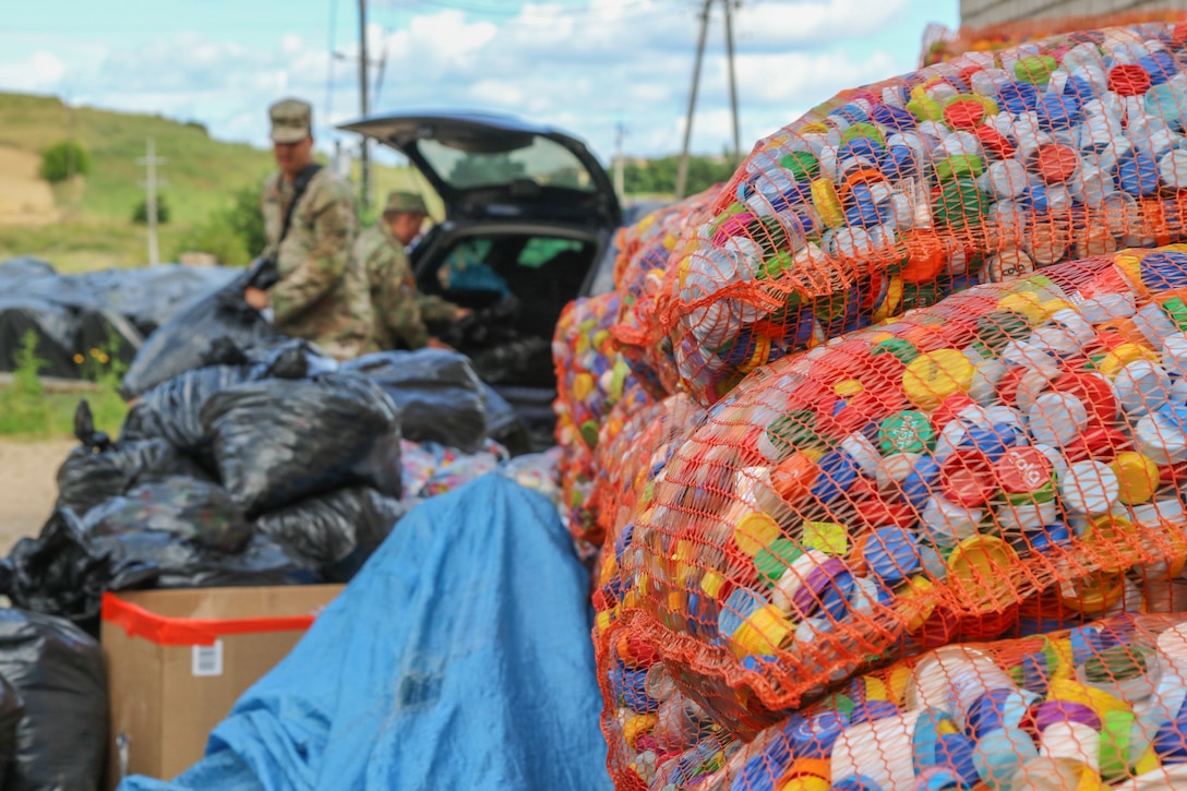 Soldiers unload bags of bottle caps.