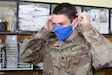 U.S. Army Spc. Alex L. Jackson, 248th Medical Company (Area Support) communications specialist, puts on one of the estimated 2,000 handmade cloth masks sent from the United States to the unit at Al Asad Air Base, Iraq, July 10, 2020. When the masks arrived in May, troops and civilians at the base were able to use the masks to help prevent the spread of COVID-19. Coalition Forces remain united and determined in their mission to degrade and defeat Daesh. (U.S. Army by Sgt. 1st Class Gary A. Witte)