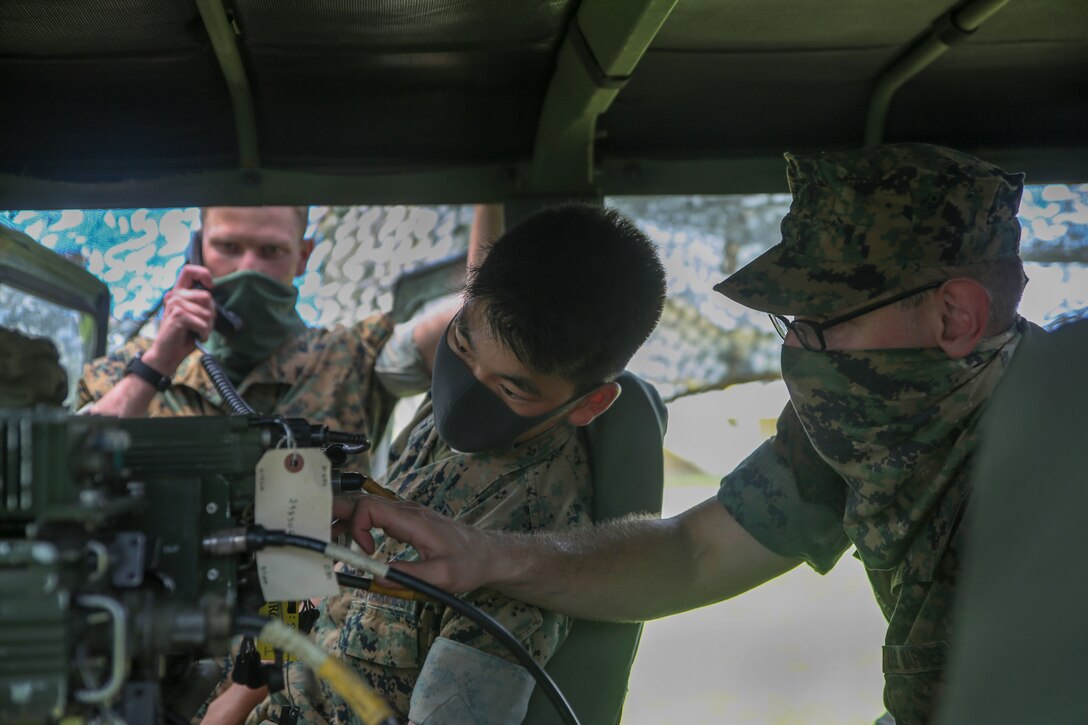Three Marines check a radio in a vehicle.