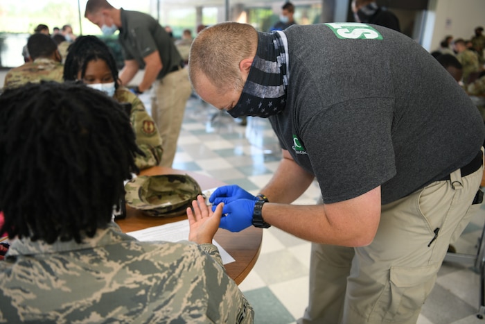 Photo shows a man pricking a woman's finger with a needle.