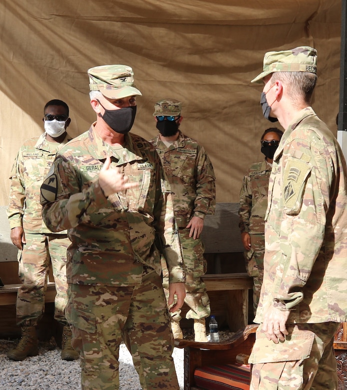 Members of the Afghanistan District watch as Colonel Mark Geraldi bids farewell to Colonel Chris Becking as he completes his tour as the outgoing commander.