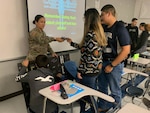 U.S. Army Spc. Maritssa Quintanilla hands markers to a student at Pharr-San Juan- Alamo Early College High School in San Juan, Texas Jan. 31, 2020.