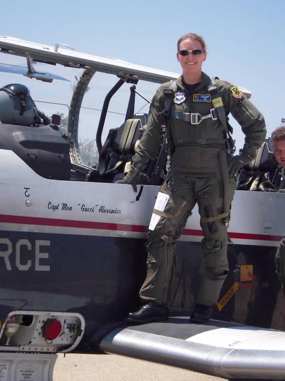 An Airman posing for a photo near a plane.