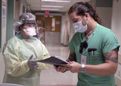 Cesar De La Vega (right) ensures Maj. Kay Bolin properly dons her personal protective equipment in an intensive care unit at Brooke Army Medical Center July 17.