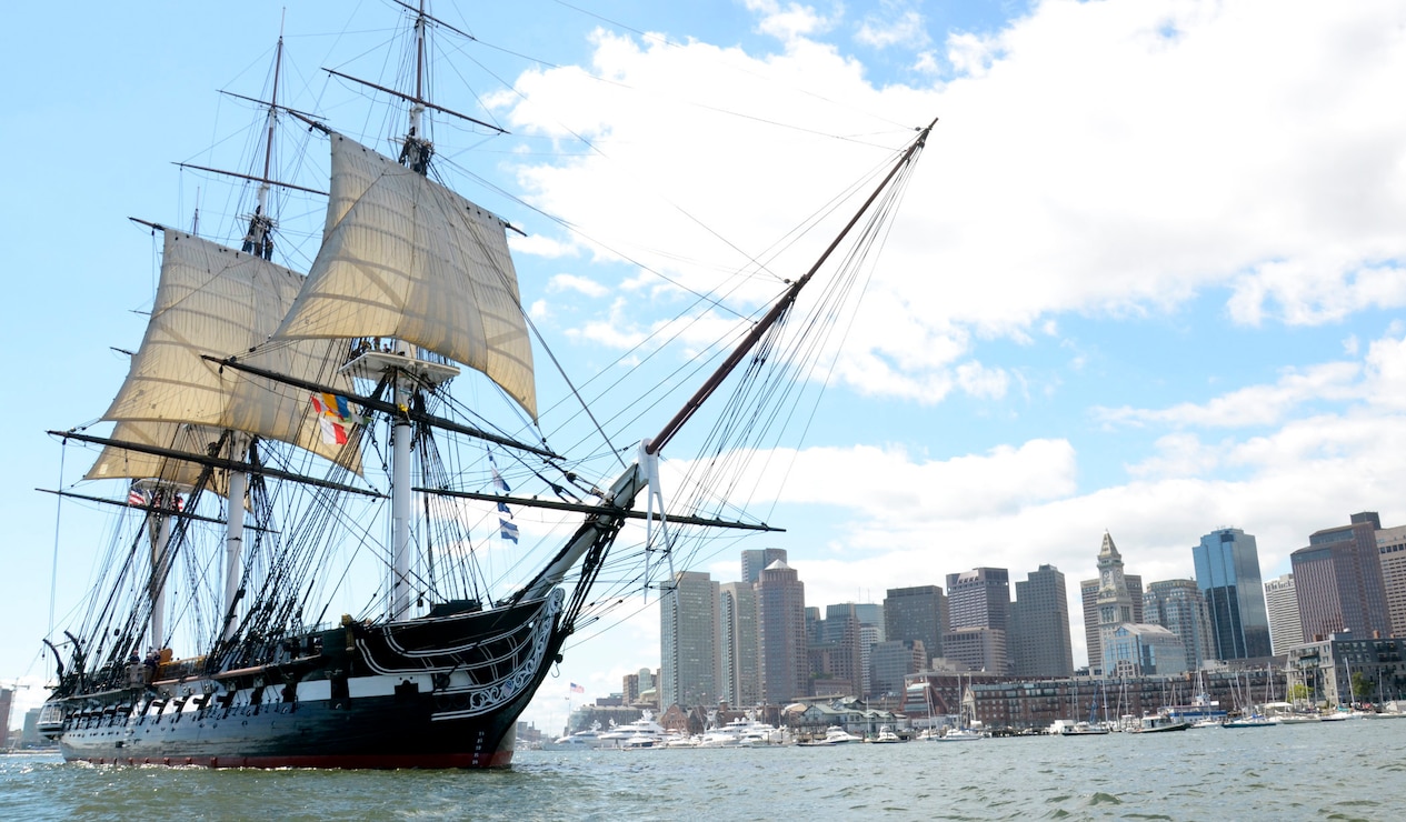 USS Consitution sailing with boston skyline in the background