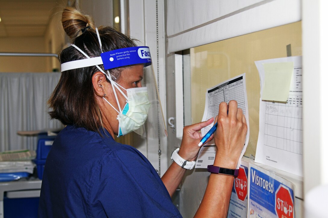 An Air Force nurse wearing personal protective equipment completes a patient inventory sheet.