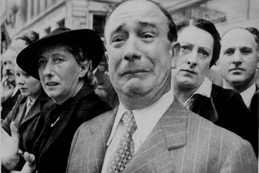 A Frenchman weeps as German soldiers march into Paris.