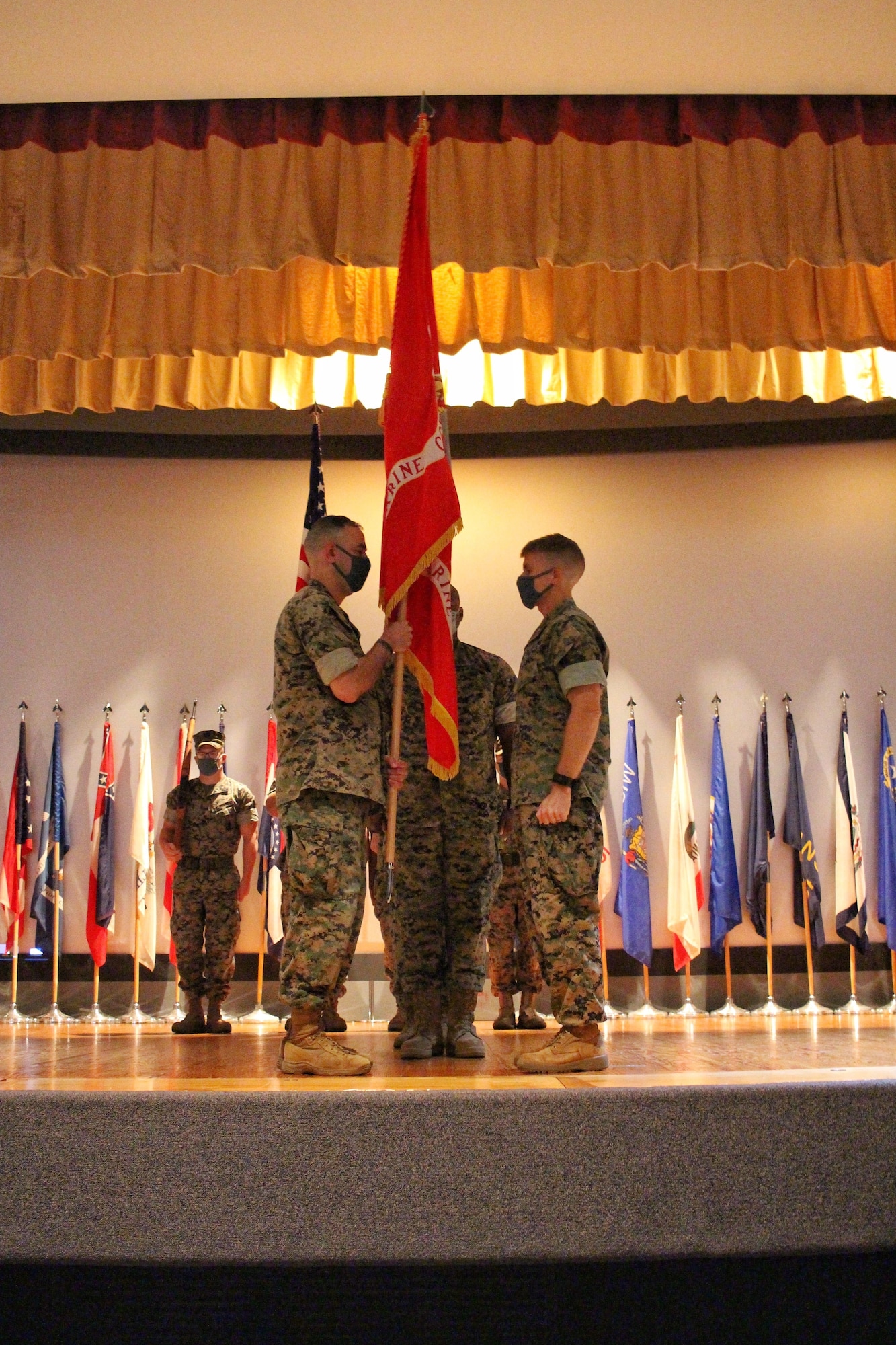 U.S. Marine Lt. Col. Arturo Derryberry, Goodfellow Marine Detachment incoming commander, accepts the guidon from outgoing commander Lt. Col. Earl Patterson at the base theater on Goodfellow Air Force Base, Texas, July 17, 2020. Precautions for COVID-19 included controlled seating and the wearing of masks during the ceremony. (Courtesy Photo)