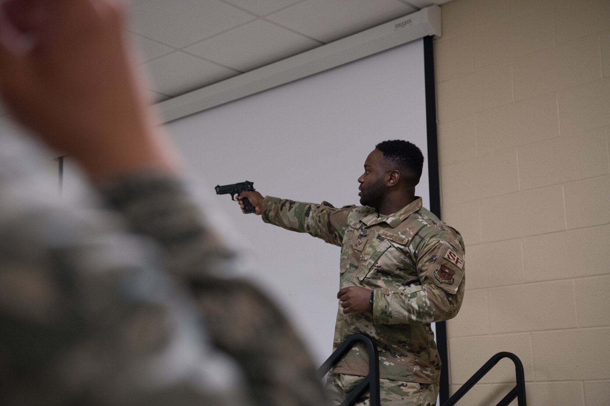 Staff Sgt. David Ikner demonstrates how to handle a Beretta M9 pistol safely with a class of cadets from the Air Force Reserve Officer Training Corps July 9, 2020, at the Combat Arms Training and Maintenance facility on Maxwell Air Force Base, Alabama.