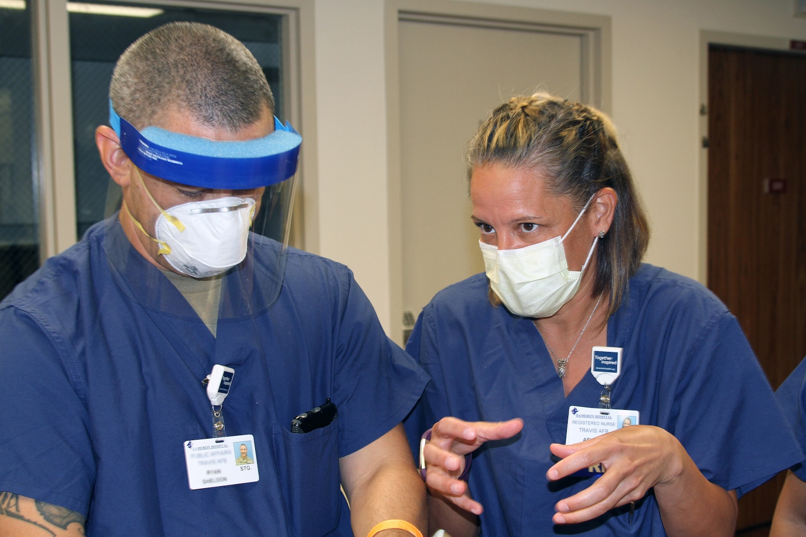 Image of U.S. Air Force Capt. Ashley Ritchey instructing Staff Sgt. Ryan Sheldon of the California Army National Guard on proper application of medical personal protective gear.