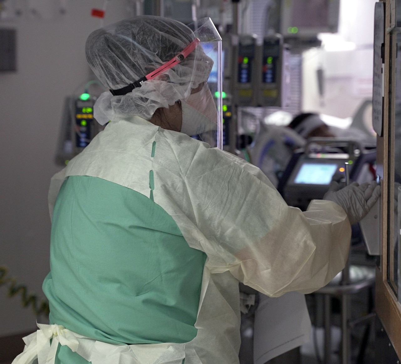 A nurse enters a patient room in a COVID-19 intensive care unit.