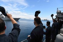 Sailors aboard mine countermeasures ship USS Pioneer (MCM 9) wave at Japan Maritime Self-Defense Force (JMSDF) Sailors.