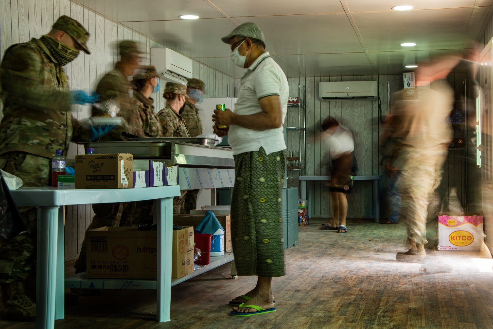 People wearing masks at Ali Al Salem Kuwait working and being served by Airmen.