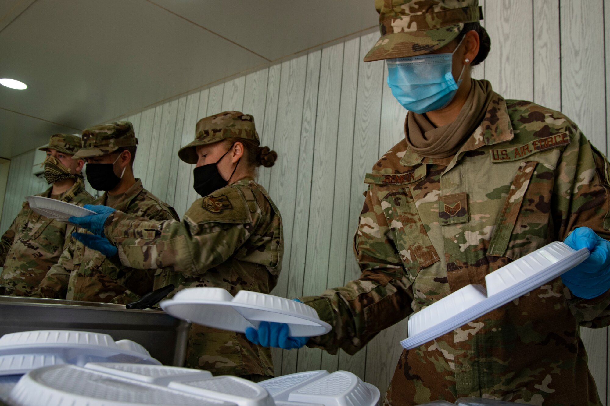 People wearing masks at Ali Al Salem Kuwait working and being served by Airmen.