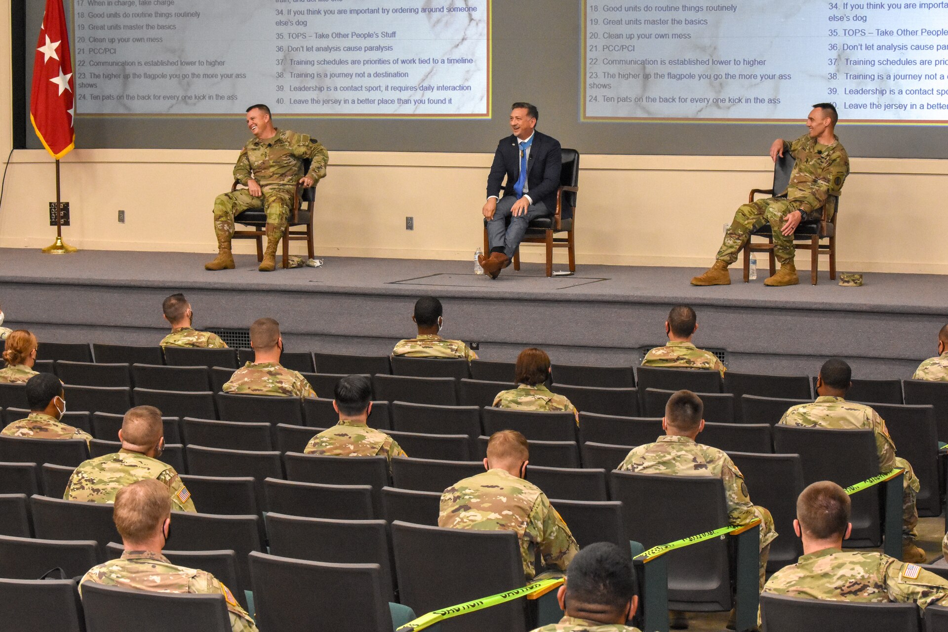 Soldiers sitting in a row wearing masks and social distanced.