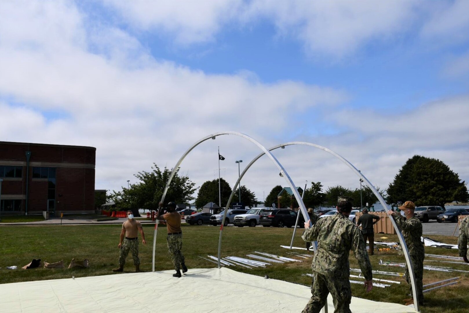 NMRTC employees raise the first of five shelters at the Navy’s medical clinic in Newport, Rhode Island, on July 7, 2020. The Defense Logistics Agency partnered with Air Force and Navy medical to provide shelters for COVID-19 screening at naval medical facilities in the Northeast.