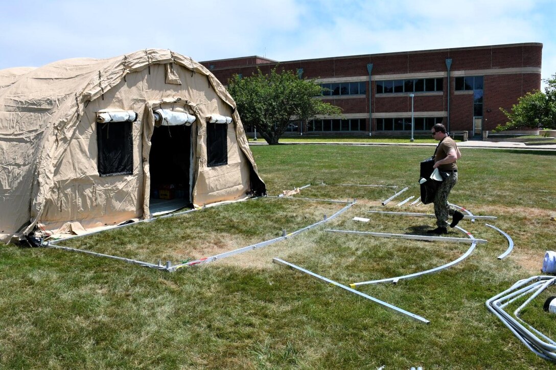 NMRTC employees raise the first of five shelters at the Navy’s medical clinic in Newport, Rhode Island, on July 7, 2020. The Defense Logistics Agency partnered with Air Force and Navy medical to provide shelters for COVID-19 screening at naval medical facilities in the Northeast.