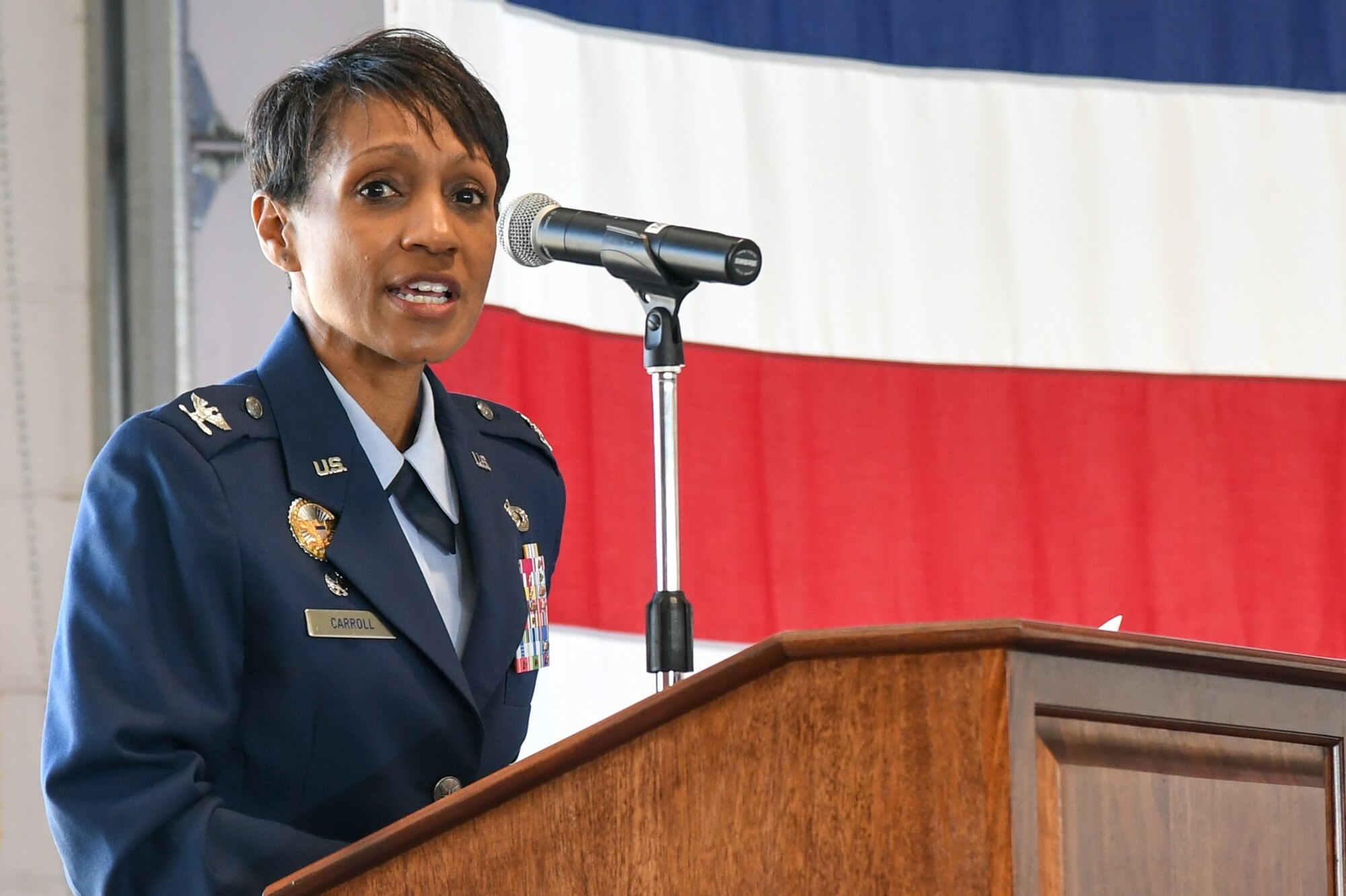 Col. Jenise M. Carroll speaks from behind a podium during her assumption of command of the 75th Air Base Wing.