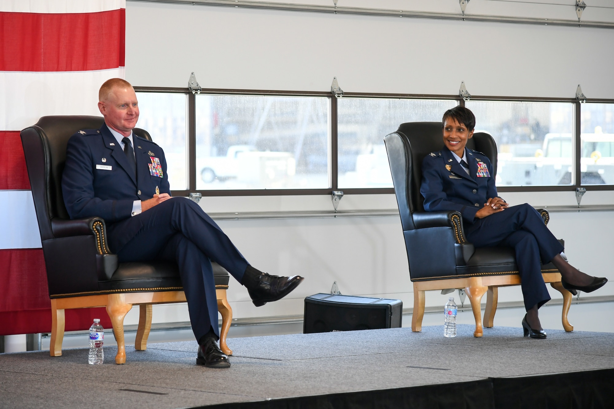 Col. Jenise M. Carroll, right, and Col. Jon A. Eberlan seated on stage during the 75th Air Base Wing change of command ceremony.
