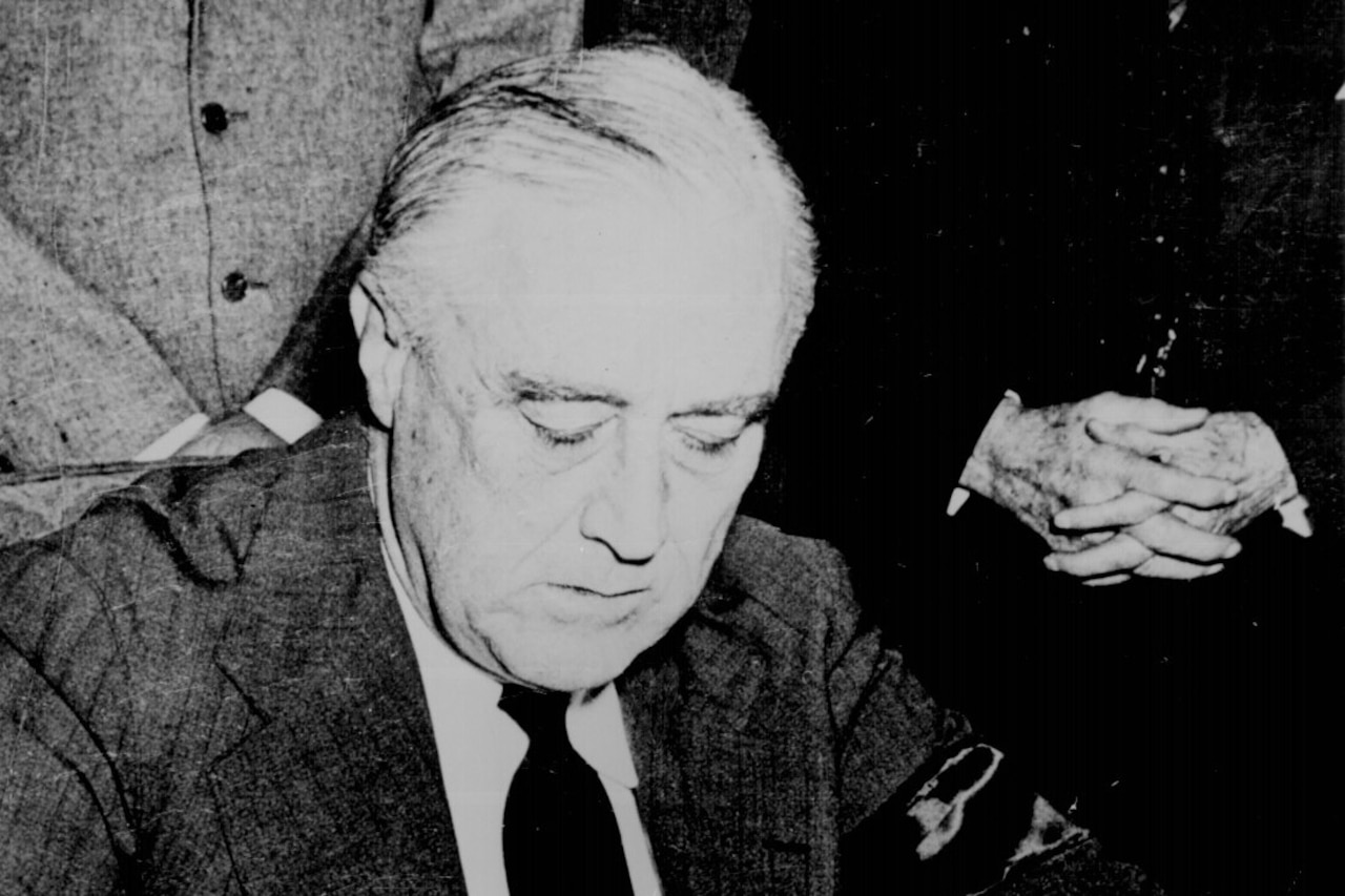 A man looks down as he signs a document.