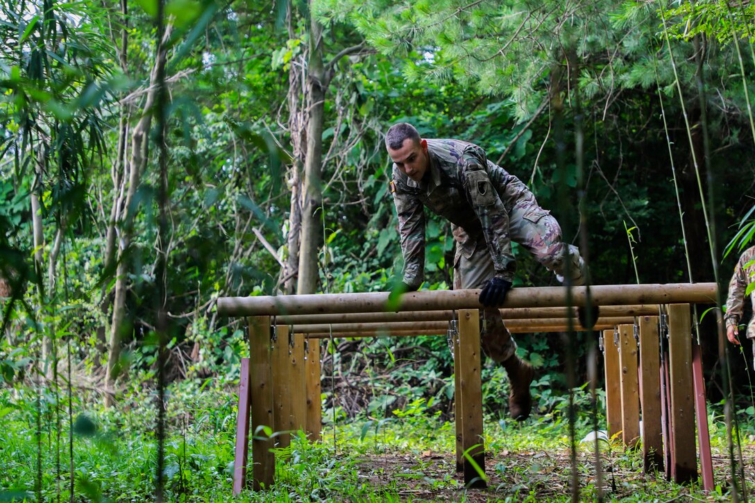 A soldier wearing gloves clears an outdoor obstacle during the 2020 Best Warrior Competition.