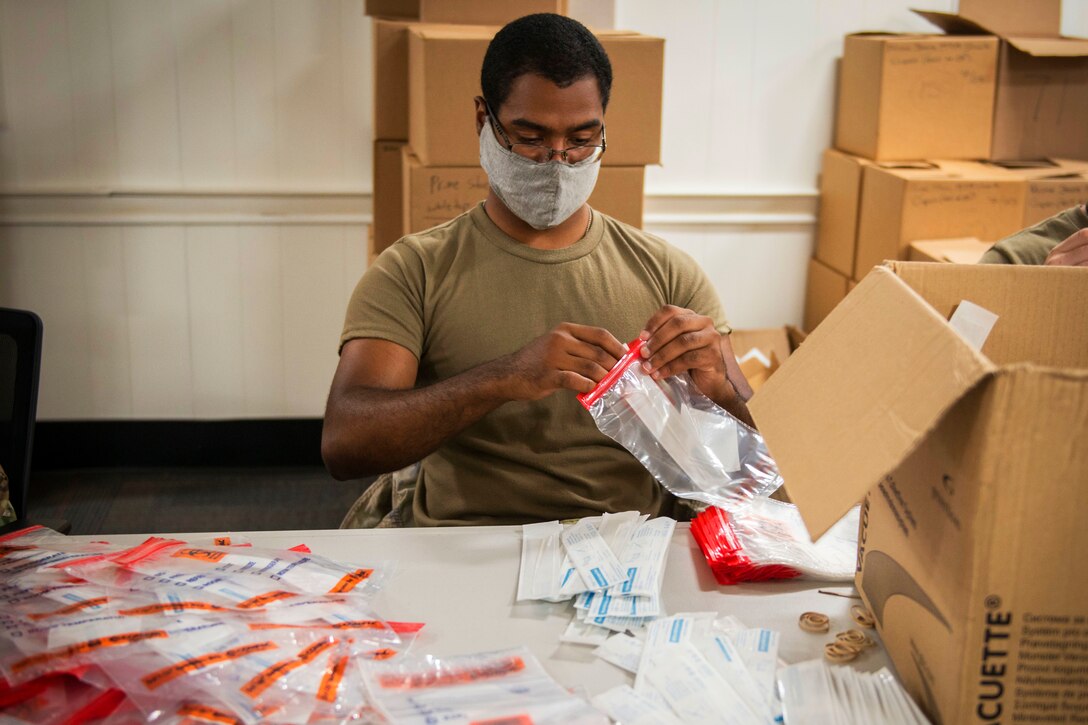 A soldier wearing a face mask assembles COVID-19 test kits.