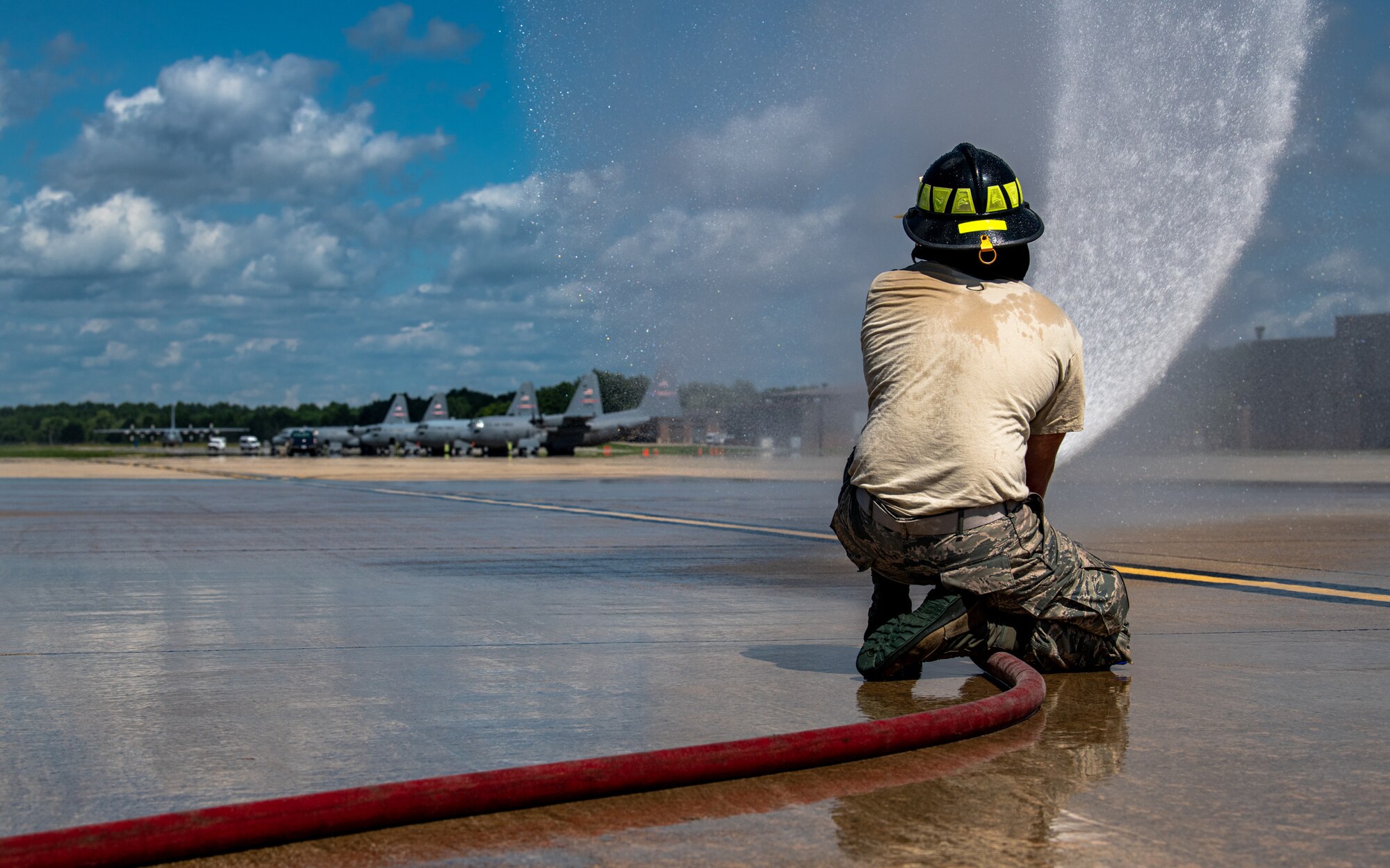 A firefighter with the 910th Fire Department sprays water from a fire hose, July 24, 2020, on the flightline at Youngstown Air Reserve Station. Airmen from the station were completing their Seasonal Training requirements for pump operations. ST is a program where Airmen raise their skill level from apprentice to a journeyman.