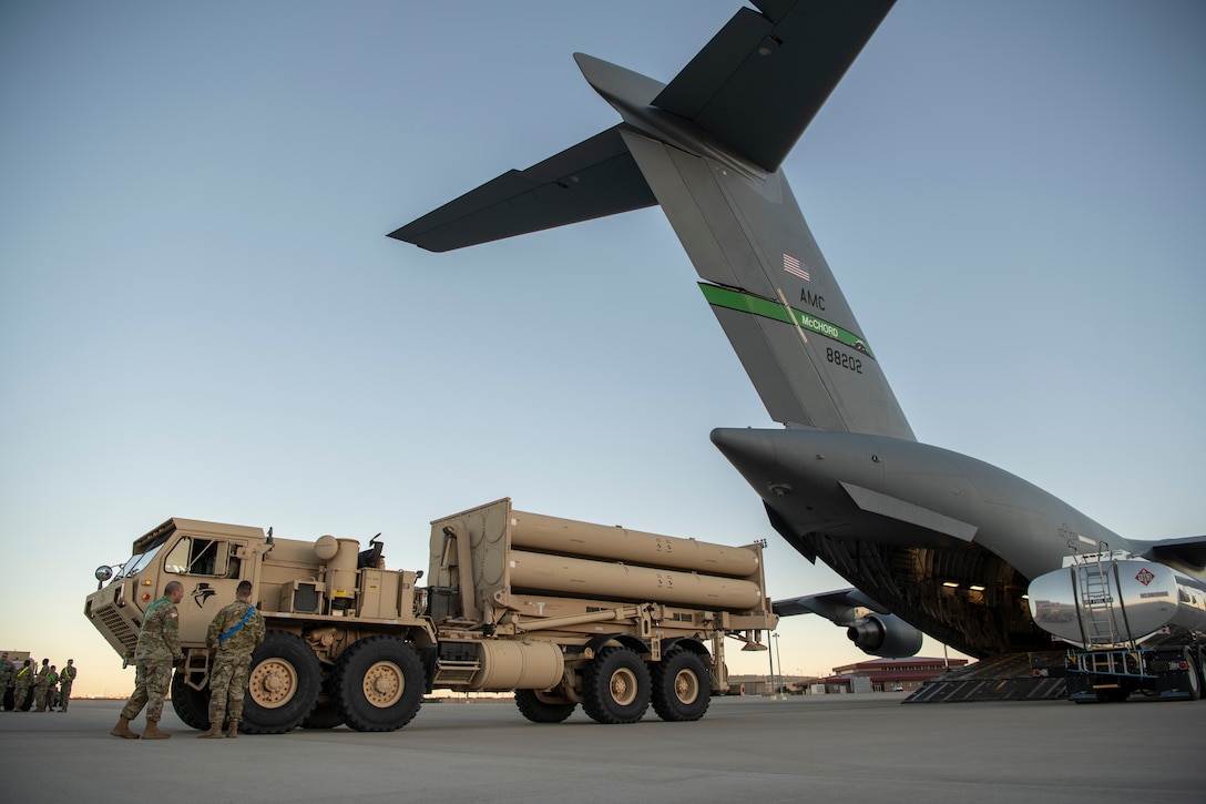 A large truck backs onto a large cargo aircraft.