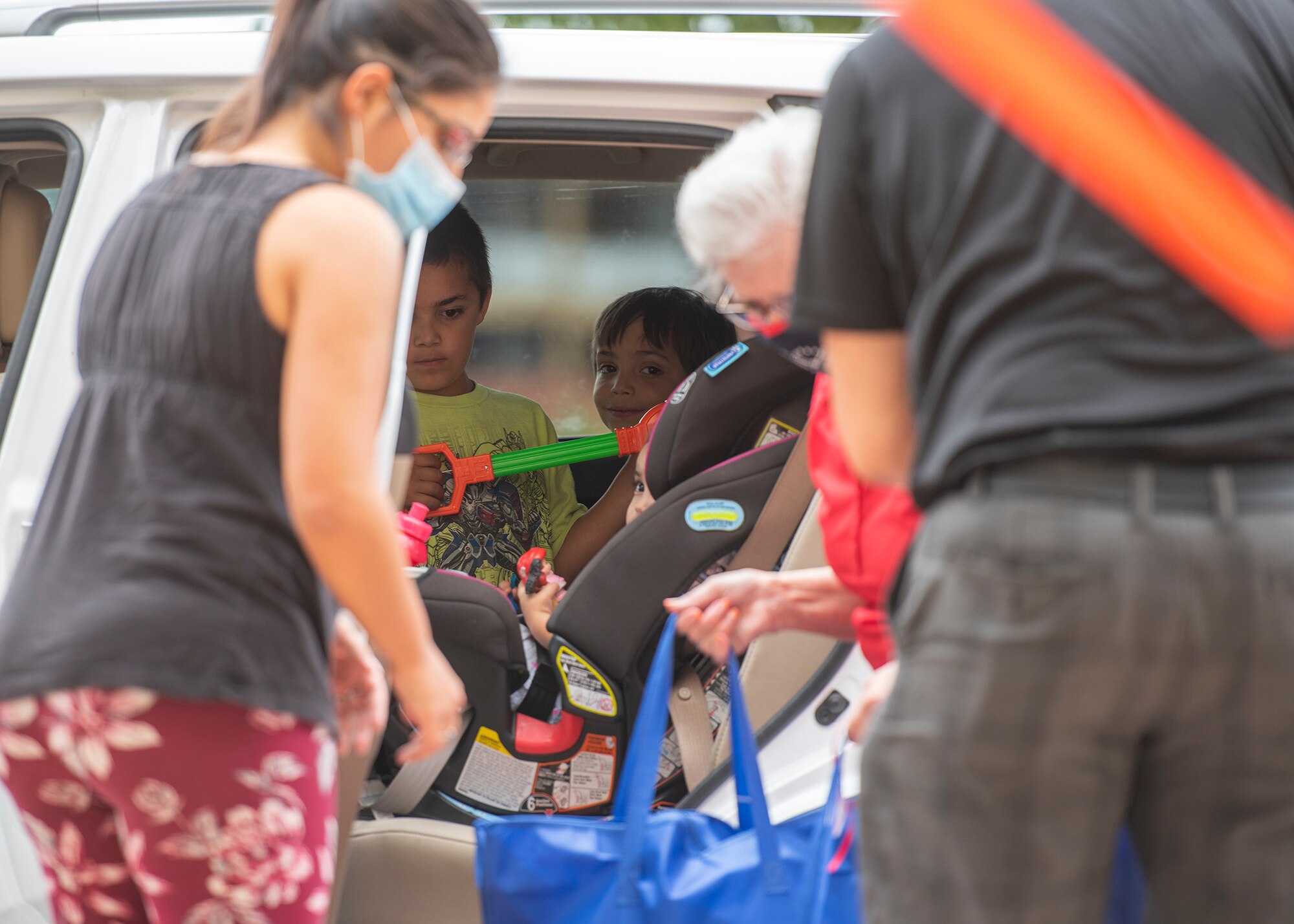 Children watch as volunteers load school supplies and toys into a car during the Back to School Bash drive-thru July 23, 2020, at the Gila Bend Arena in Glendale, Ariz.