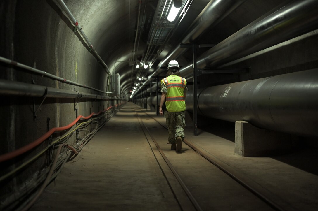 A sailor walks a portion of tunnels at a facility.