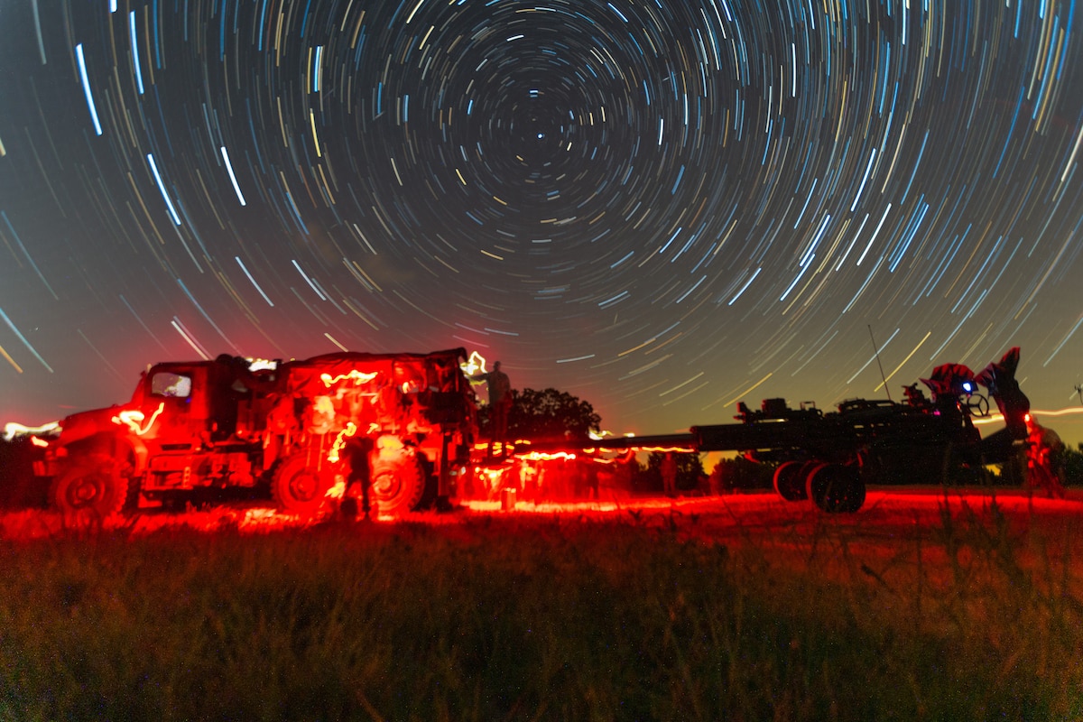 Marines work on vehicles bathed in red light.